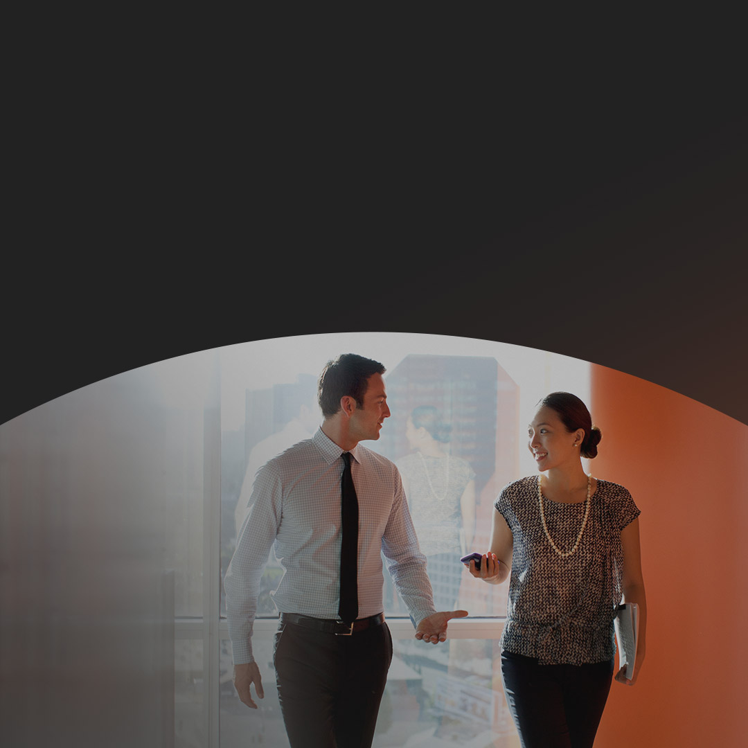 Two people walking and talking in office.