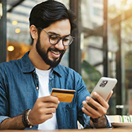 Man looking at phone and holding credit card. 