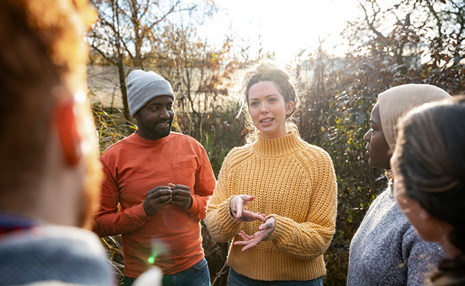 A woman giving a talk outside to several listeners.