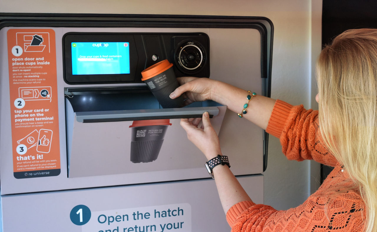 Woman dropping paper cup into recycling machine
