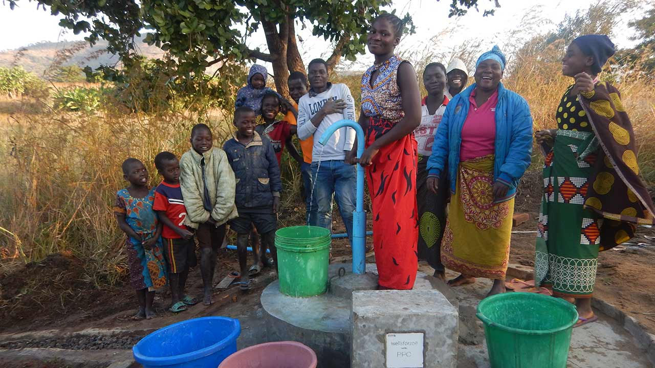Smiling people at a water pump.