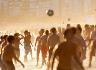People playing ball on the beach at sunset