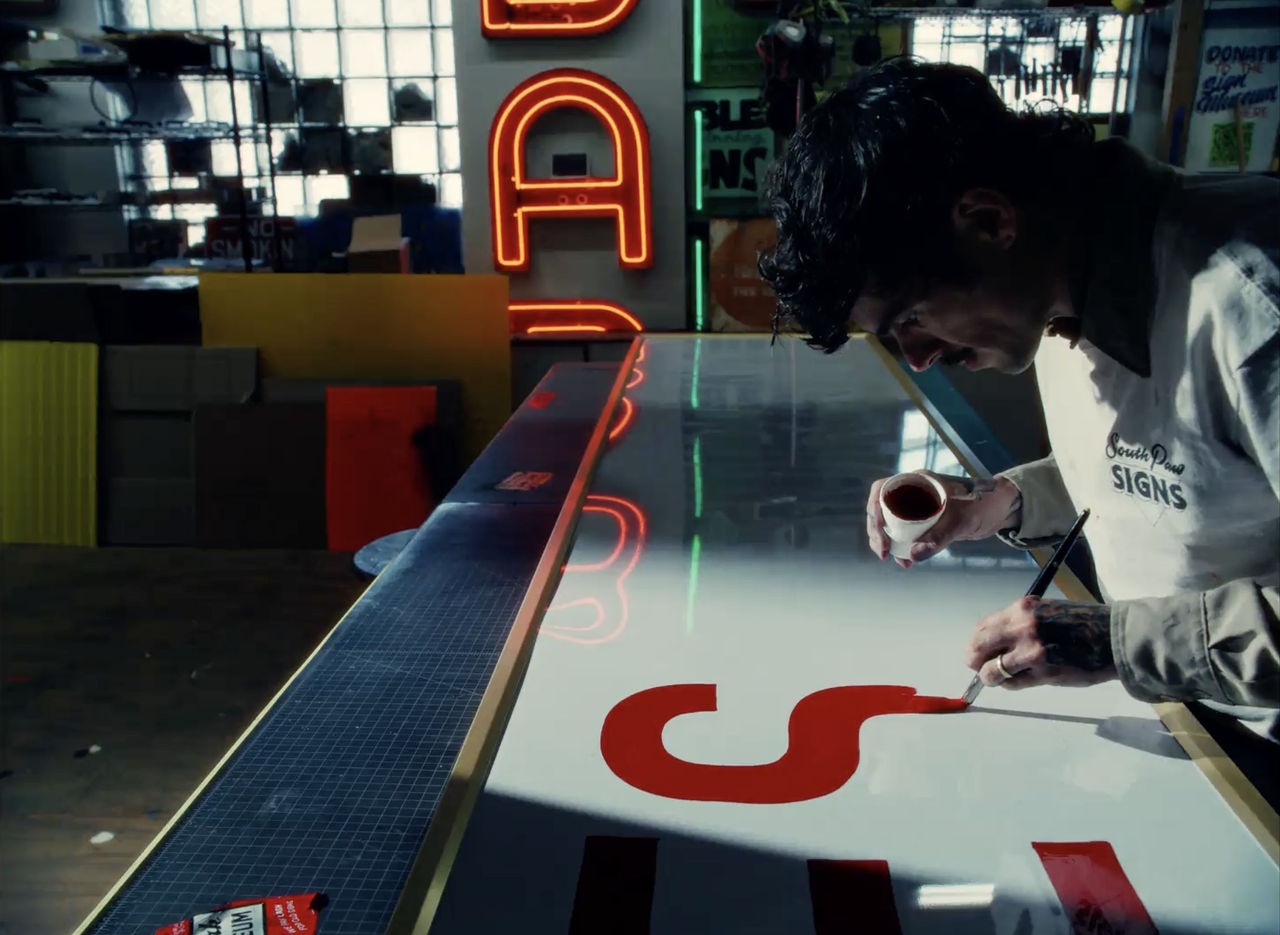 A man paints a sign.