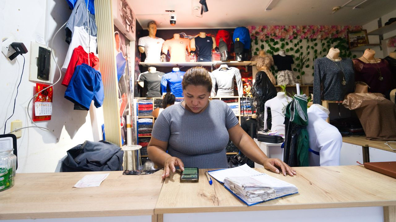 Fabiola looks at a digital app at the counter in her sportwear store. 