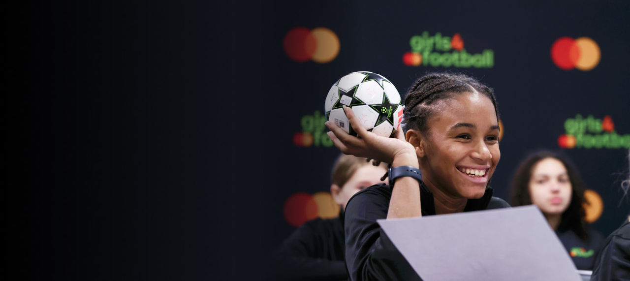 χαμογελαστό κορίτσι που κρατάει μια μπάλα ποδοσφαίρου στην τάξη