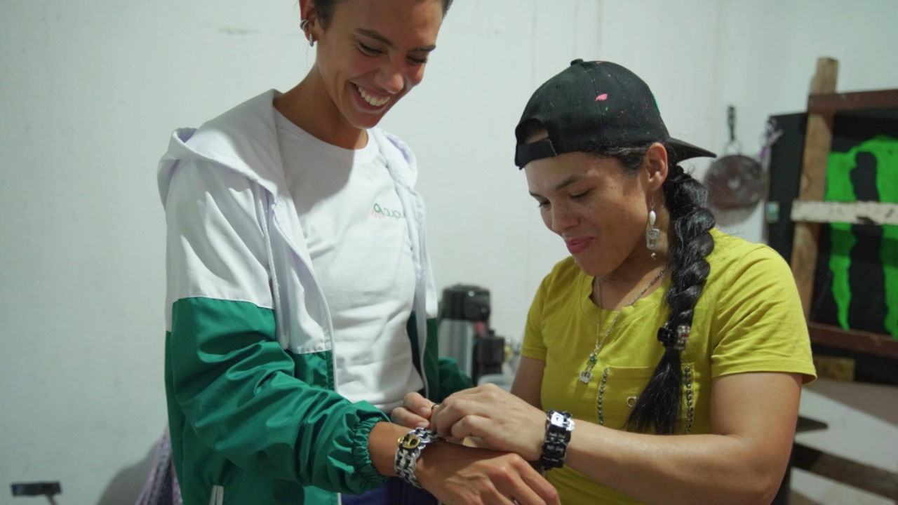 A jewelry entrepreneur clasps a bracelet on Mercedes Bidart's wrist. 