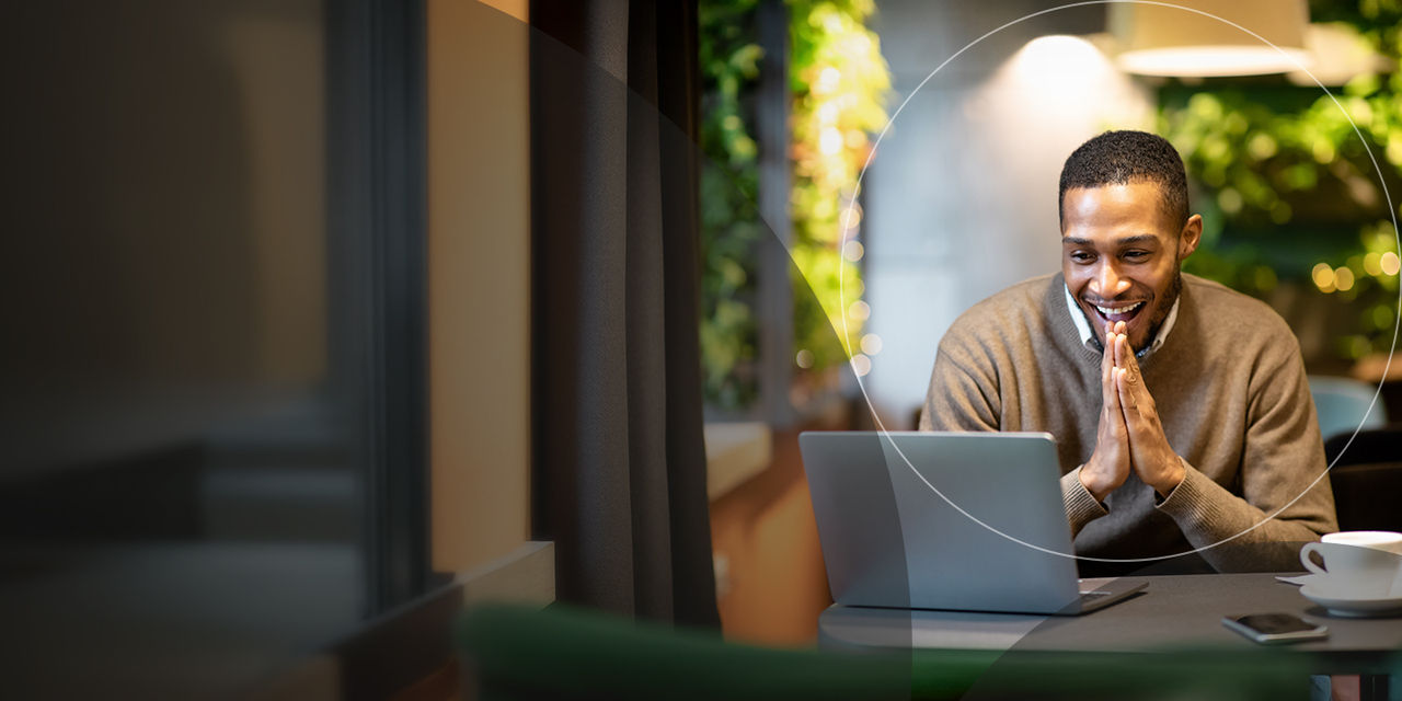 Young businessman using laptop sitting at cafe.