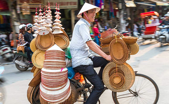 Bicycle seller riding through a street in Asia.