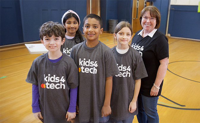 Kids and their teacher wearing kids 4 tech t-shirts.