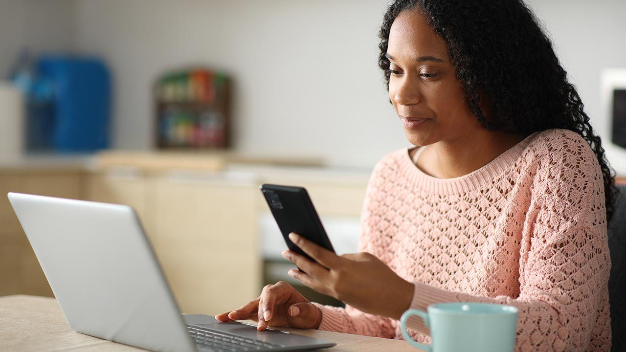 Woman using two devices in home office.