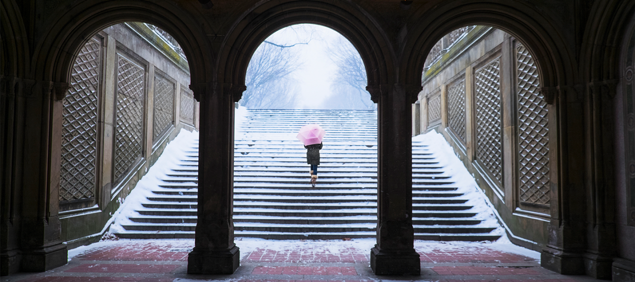 雪景色の中を階段で上に上がっていく女性