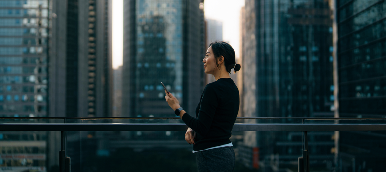 高層ビル群の前で電話をする女性