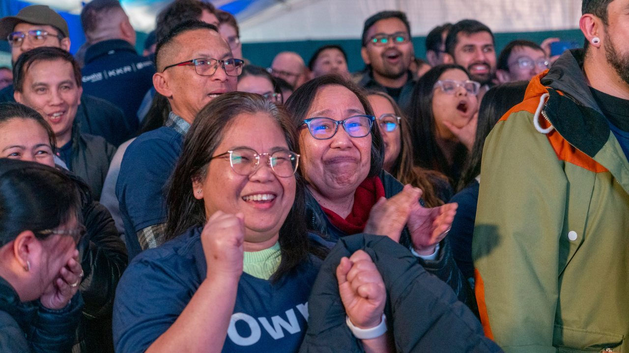 A group of CoolIT employees clap excitedly at a company meeting. 