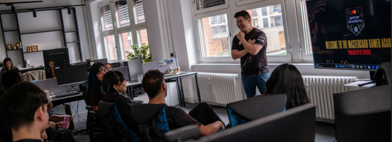 Члены Mastercard Gamer Academy беседуют с представителем G2 в офисе перед экраном.