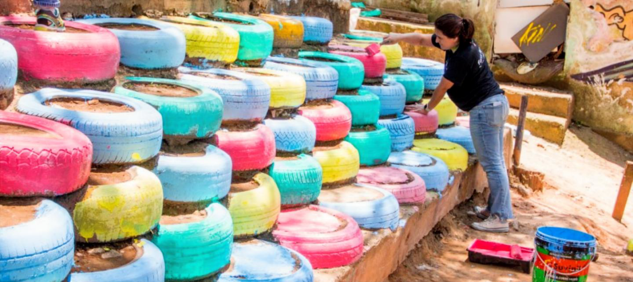 Rita Krejici paints tires stacked as a retaining wall . 