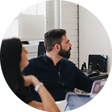 Compañeros de trabajo colaborando en una mesa con computadoras portátiles.