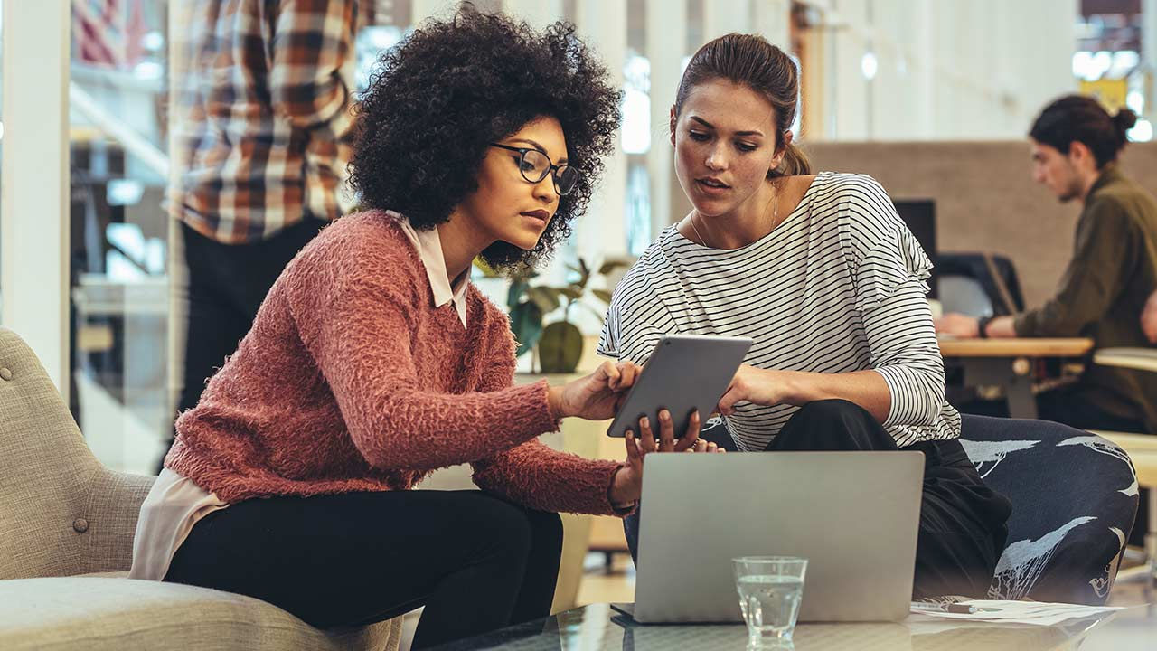 Compañeras de trabajo discutiendo el trabajo en una oficina moderna.