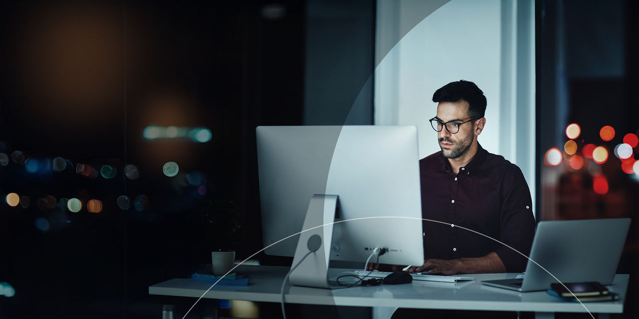 Homme assis à un bureau sur un ordinateur.