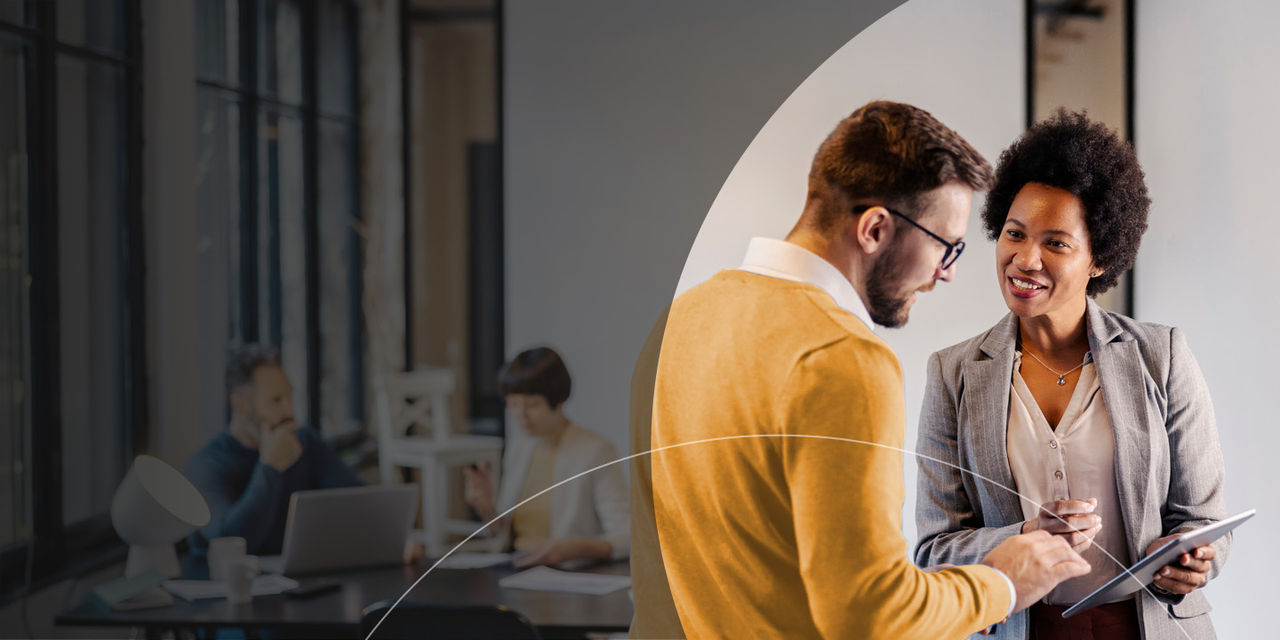Deux personnes discutent dans un bureau, tout en tenant une tablette.