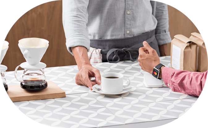 Une personne paie son café avec une montre sans contact.