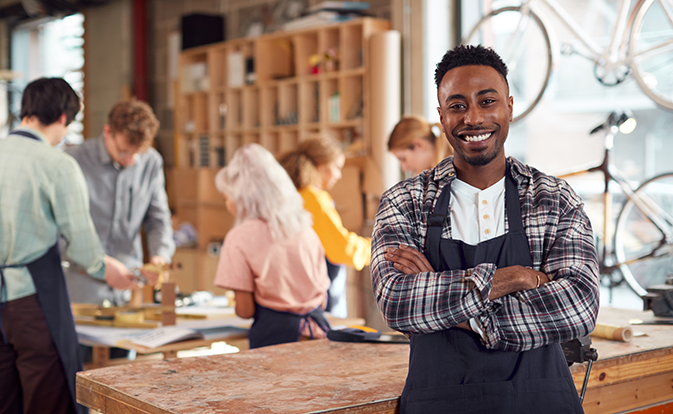 Homme souriant à la caméra alors qu’il se tient au milieu d’un atelier de team building