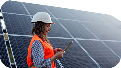 Femme portant un casque de sécurité, utilisant un smartphone devant une rangée de panneaux solaires.