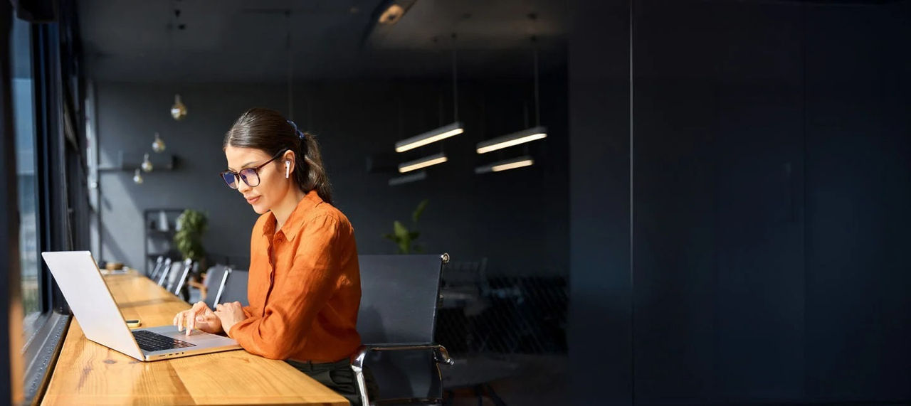 امرأة ترتدي نظارات تعمل على حاسوب محمول