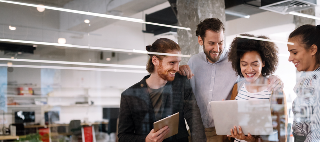 مجموعة متنوعة من الأشخاص اجتمعت حول حاسوب محمول، منخرطين في نقاش وينظرون إلى الشاشة معًا.