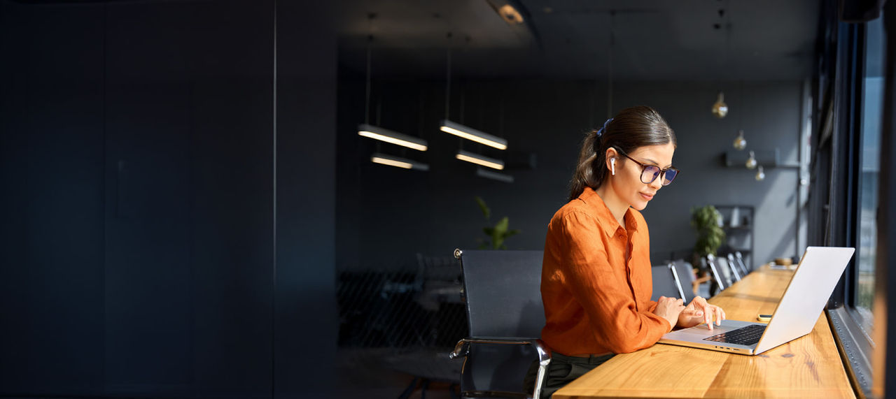woman wearing glasses working on a laptop