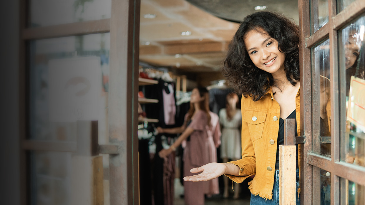 A woman stands outside a shop window, looking at the products showcased inside.