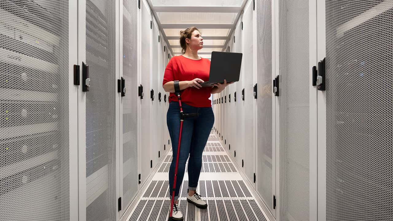 woman holding laptop while standing in a server room