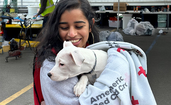Woman holding a dog in a blanket.