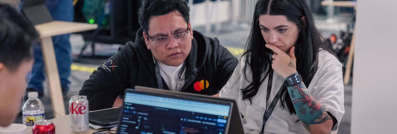 Two cybersecurity experts look at a laptop.