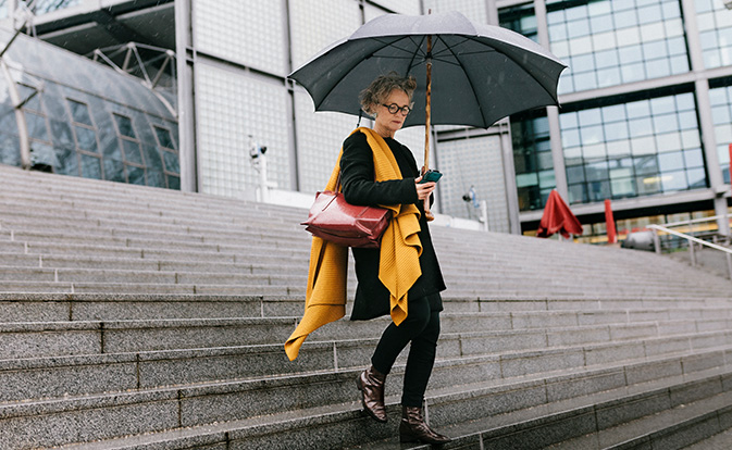 Femme descendant des marches et regardant son téléphone pour authentifier son identité. 