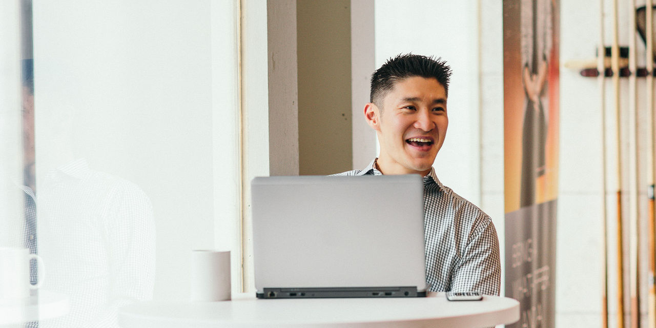 Un homme souriant utilise son ordinateur portable