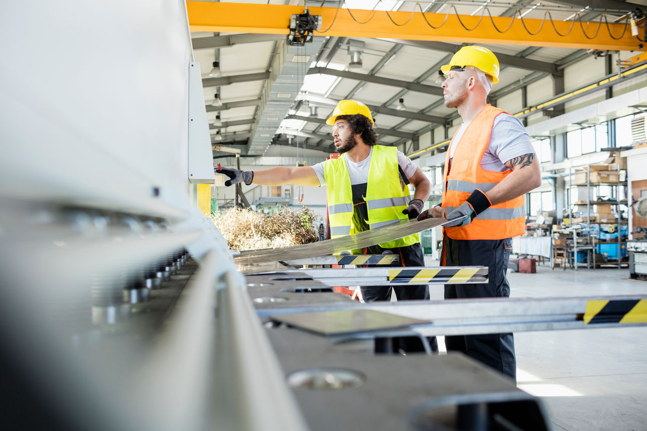 Male manual workers manufacturing sheet metal at industry