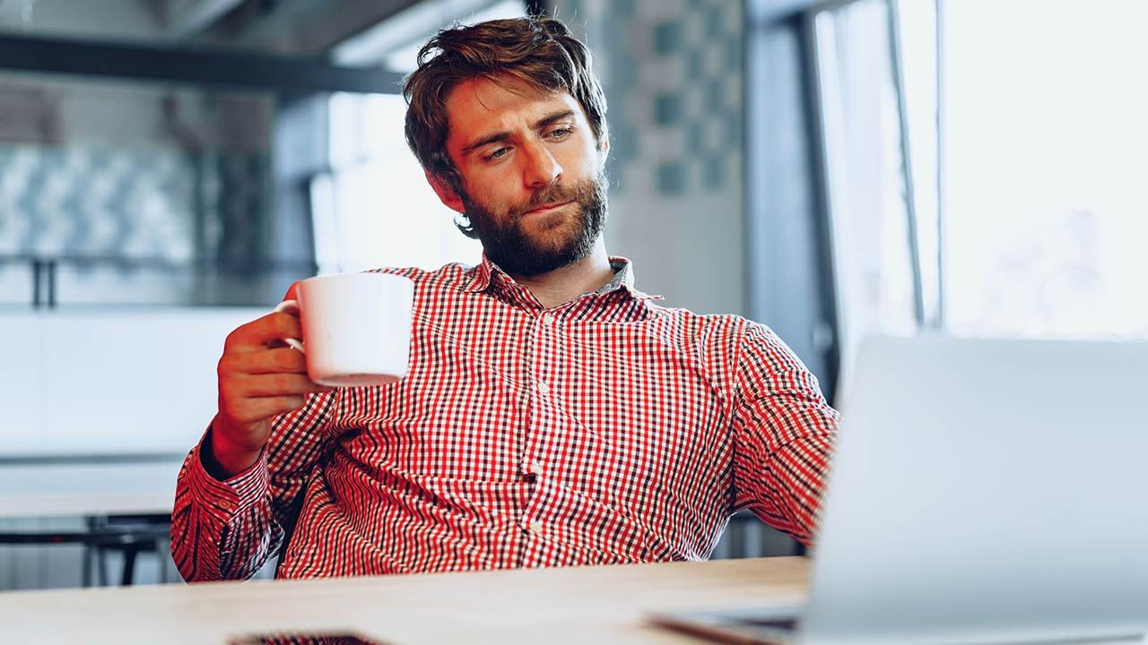 Man contemplating at computer screen in office.