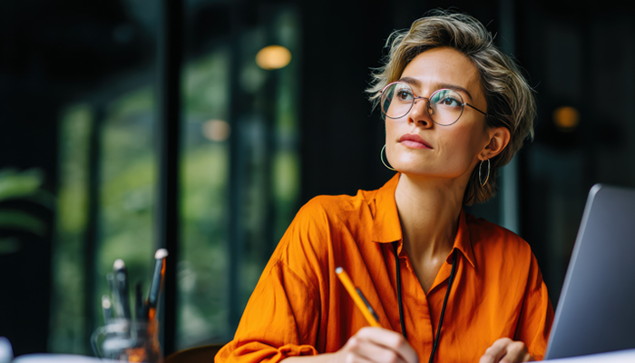 Woman on her laptop taking notes with a pencil