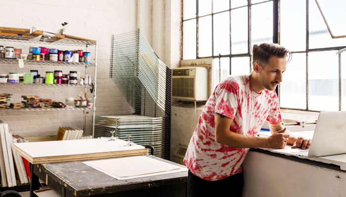Small business owner using a laptop in a print workshop