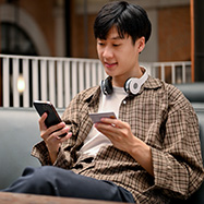 Man looking at phone and holding credit card. 