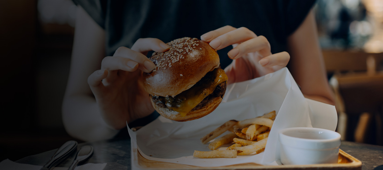 Woman holding a cheeseburger at a restaurant