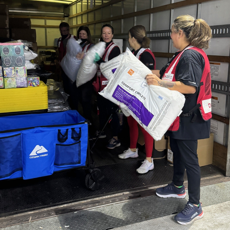 People in Red Cross vests pack a truck with supplies.