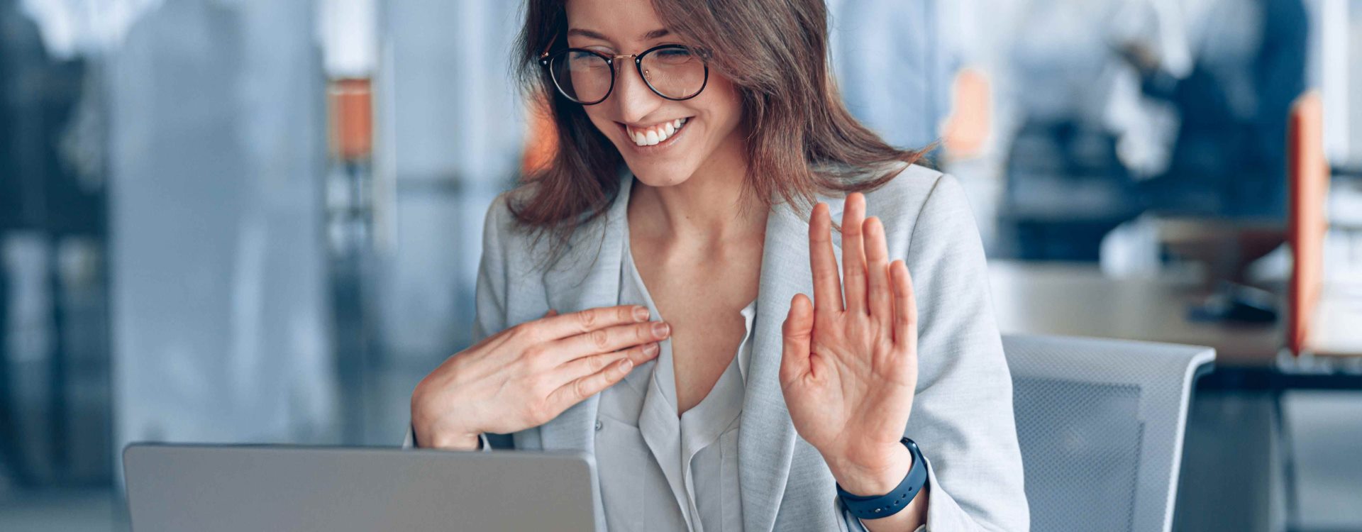 A woman uses sign language while looking at her computer in an office.