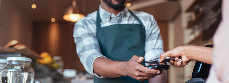 A person makes a mobile contactless payment at a coffee shop