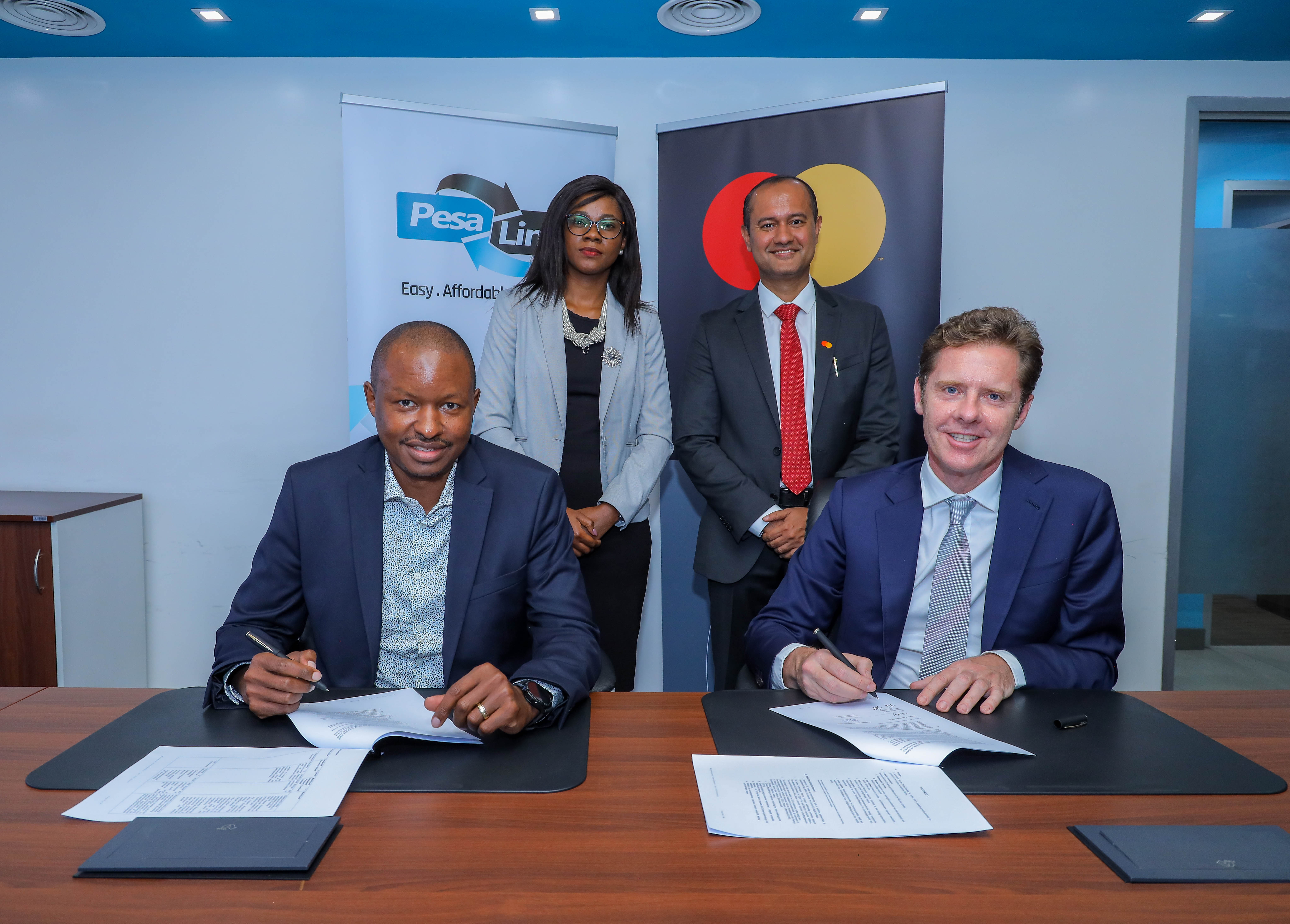 Gituku Kirika, CEO of PesaLink (front left) and Mark Elliott, Division President for Mastercard, Sub-Saharan Africa, Mastercard (front right) sign a Memorandum of Understanding to create innovative, digital-first payment solutions designed to boost the adoption and usage of digital payments and accelerate Kenya’s transition to a cash-lite economy. They are joined by Chief Strategy and Transformation Officer, IPSL, Plounne Oyunge (back left) and Shehryar Ali, Country Manager for Mastercard, East Africa (back right).