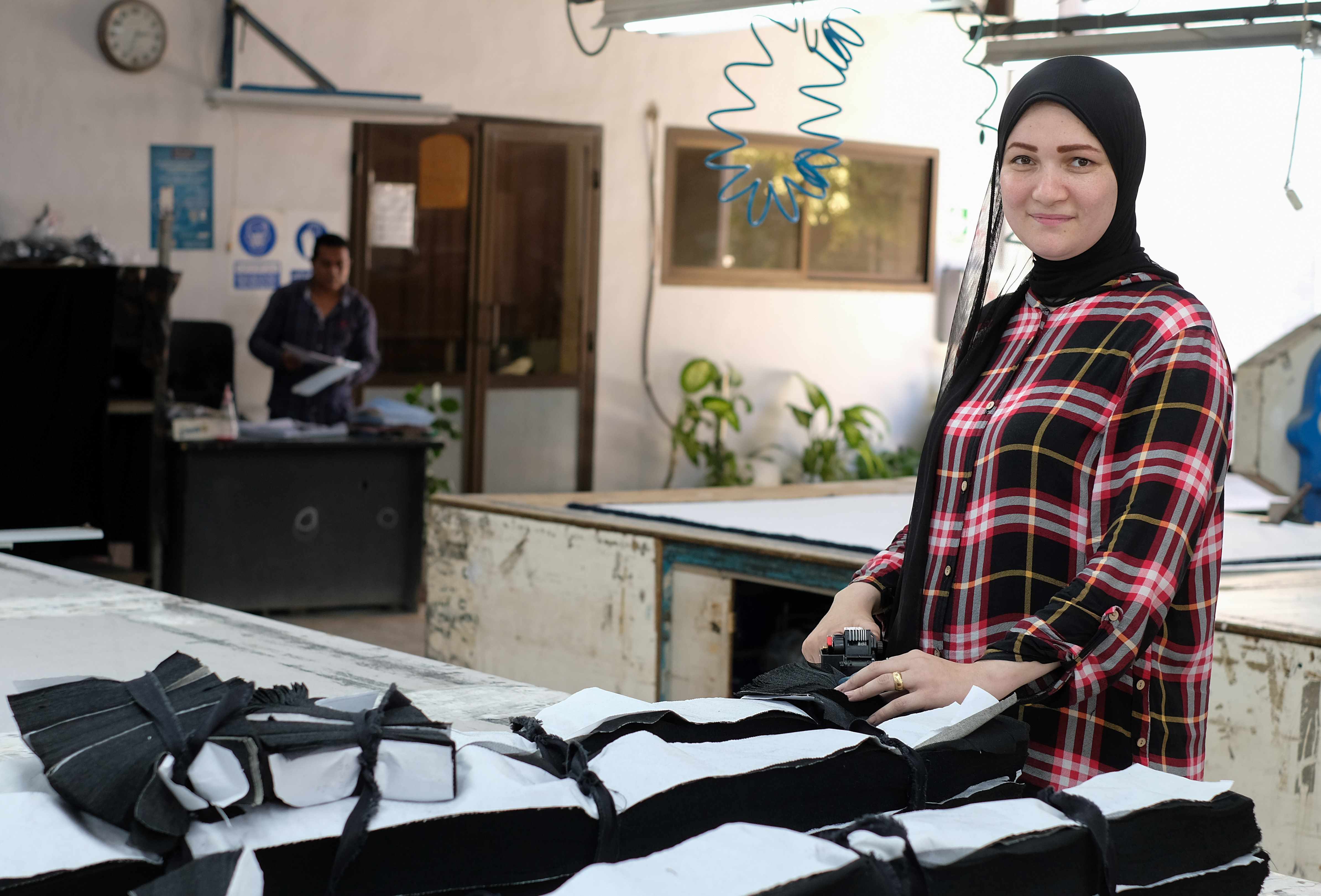 A garment factory worker stands over a table. 