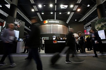 IMAGE DISTRIBUTED FOR MASTERCARD - Visitors walk past the Mastercard booth at the 2018 Mobile World Congress on Monday, Feb. 26, 2018 in Barcelona, Spain. (Manu Fernandez/AP Images for Mastercard)
