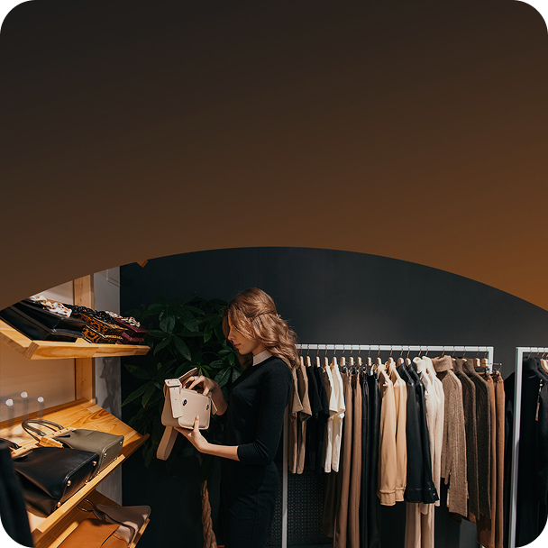 Customer in a clothing store, looking at a new handbag to purchase.