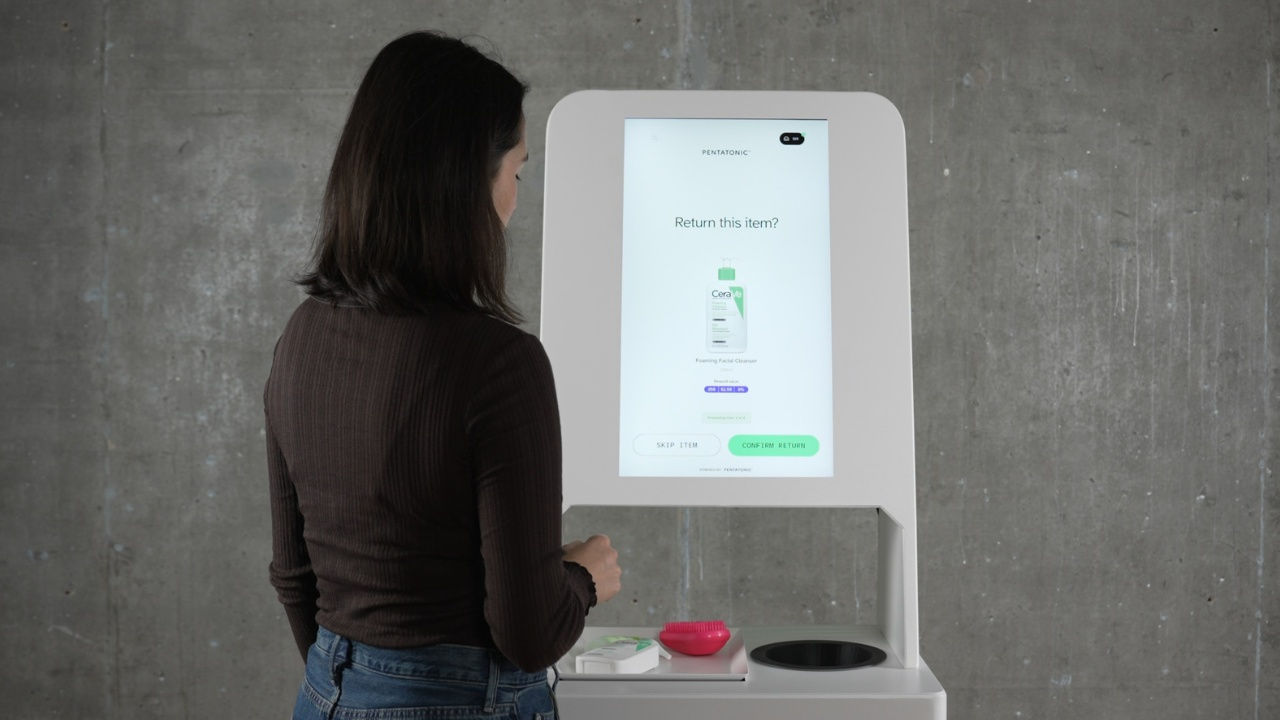 A woman stands in front of a Pentatonic PIN machine. 
