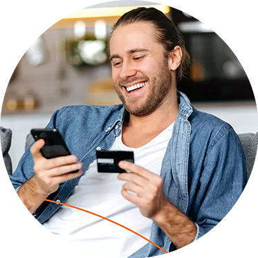 Hombre sonriendo mientras sostiene un teléfono y una tarjeta de crédito.
